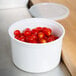 A white Cambro crock with lid full of cherry tomatoes.