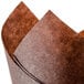 A close-up of a brown tulip-shaped baking cup made of brown and white paper.