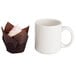 A Hoffmaster chocolate brown tulip baking cup with a cupcake next to a white mug.