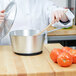 A person using a Vollrath Arkadia sauce pan to cook tomatoes.