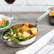 An American Metalcraft mini hammered stainless steel skillet with vegetables on a table.