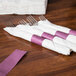 A row of Burgundy paper napkin bands wrapped around forks.