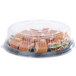 A Sabert clear plastic round high dome lid on a plastic container with a sandwich inside.