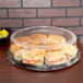 A Sabert clear plastic round high dome lid on a plastic container with sandwiches in it.