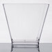 A clear WNA Comet square plastic tasting glass on a white surface.