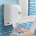 A person using a white World Dryer SMARTdri hand dryer to dry their hands.
