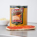 A Bonta #10 can of pizza sauce on a white background next to a pizza.