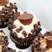 A Baker's Mark white cupcake box with a chocolate cupcake with peanut butter frosting and chocolate curls on top.