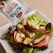 A salad with apples and nuts topped with Ken's Foods Lite Balsamic with Olive Oil Vinaigrette on a table.