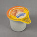A close-up of a small container of International Delight Caramel Macchiato non-dairy creamer.