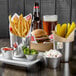 A silver container with french fries and ketchup in a Choice stainless steel round sauce cup on a table.