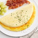 A plate with an omelet, bacon, and green garnish.