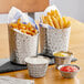 Two stainless steel round sauce cups with fries and red sauce in them.