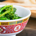 A Thunder Group Longevity melamine rice bowl filled with green seaweed on a table.