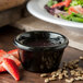 A bowl of black sauce next to a salad with strawberries.