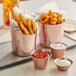 Three Choice copper-plated stainless steel sauce cups filled with sauce on a table with copper buckets of fries.