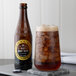 A close-up of a Boylan Diet Root Beer bottle on a table with a glass of brown liquid and ice.