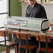 An Avantco countertop refrigerated sushi display case on a counter in a sushi bar with a chef standing behind it.