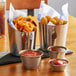 Three Acopa stainless steel French fry holders filled with fries and red sauce.