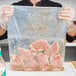 A person holding a 14" x 24" heavy weight plastic freezer bag filled with meat.