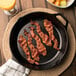 Close up of Kunzler Original Hardwood Smoked Sliced Bacon cooking in a pan.