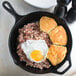 A skillet of corned beef hash with a fried egg on top.