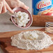 A person putting Crisco into a bowl of flour.