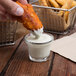 A person dipping a piece of fried food into a bowl of Ken's Chunky Bleu Cheese Dressing.