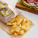 A bag of Dirty Potato Chips next to a sandwich on a table in a deli.