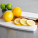 A cutting board with lemons and a lemon cut in half on a counter.