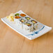 A rectangular blue and white Thunder Group Blue Bamboo melamine sashimi platter with sushi on it.