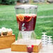A Choice clear plastic beverage dispenser with fruit and a drink dispenser on a table.