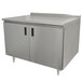 An Advance Tabco stainless steel enclosed base work table with hinged doors and a backsplash.