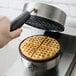 A hand using a Carnival King waffle iron grid to make waffles.