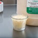 A small glass of Ken's Lite Italian Dressing next to a container of the dressing.