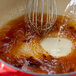 A whisk stirring brown Minor's beef base in liquid.