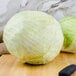 Two large heads of white cabbage on a cutting board with a knife