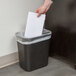 A hand putting a piece of paper into a black rectangular Continental trash can.