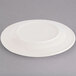 An ivory china plate with an embossed rim on a gray surface.