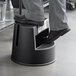 A person's feet stepping on a black Rubbermaid two-step step stool.