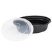 A black Pactiv plastic oval container with a clear plastic lid with a disc in the middle.