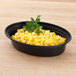 A Pactiv Newspring VERSAtainer oval microwavable container filled with corn and parsley.