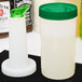 A white Carlisle plastic container with a green spout and cap.