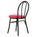 A black metal Lancaster Table & Seating hairpin chair with red vinyl seat.