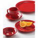 A Tuxton TuxCare red china saucer with a slice of orange on it.