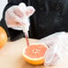 A person in gloves using a Dexter Russell grapefruit knife to cut an orange.