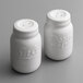 Two white ceramic Mason jar salt and pepper shakers with lids, labeled salt and pepper.