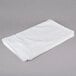 A folded white Oxford Belleeza bath mat on a gray surface.