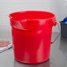 A Rubbermaid red 10 qt. bucket on a counter.