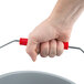 A hand holding a Rubbermaid gray bucket with a red handle.